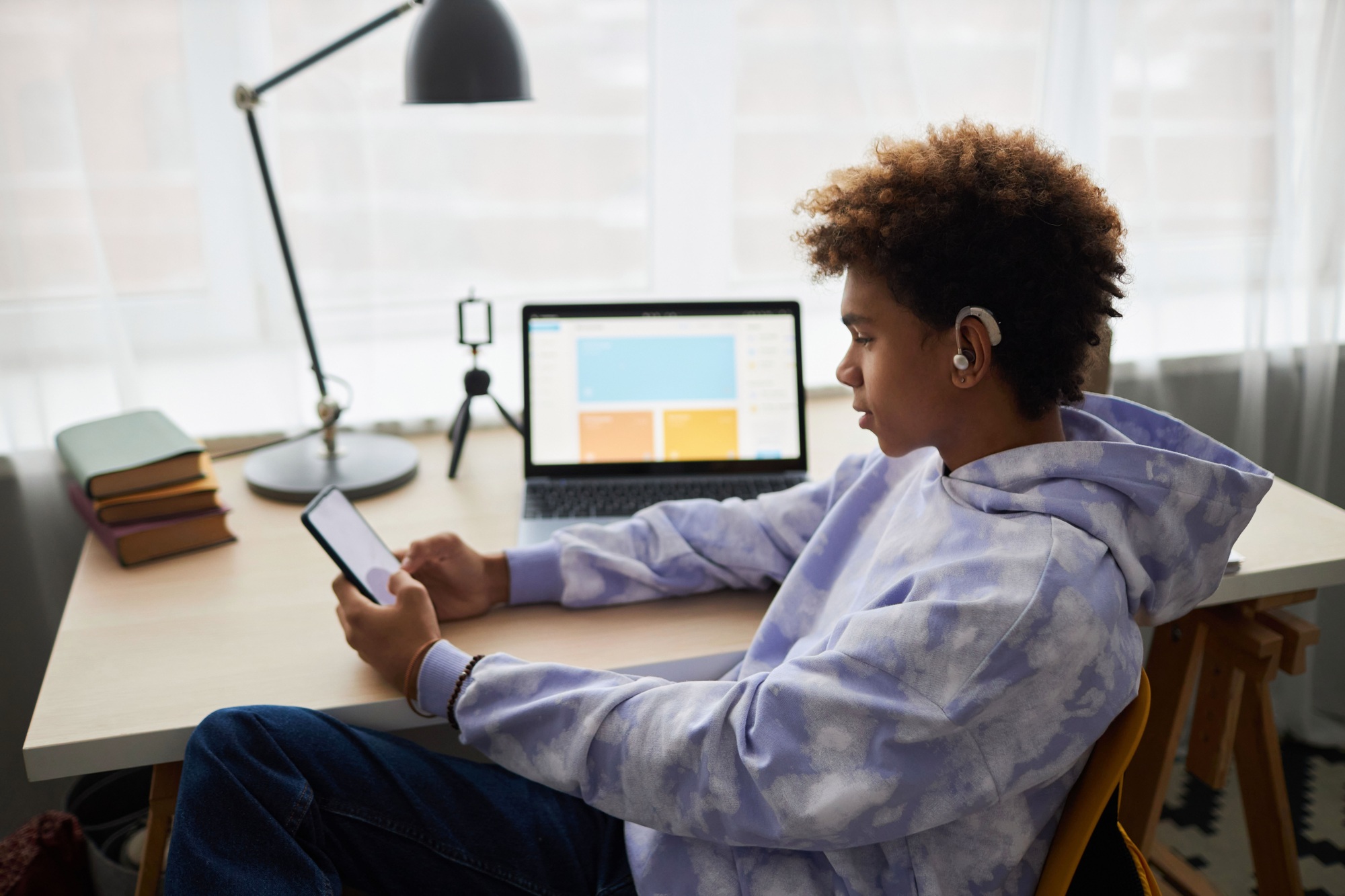 Youthful African American boy in earphones looking at smartphone screen